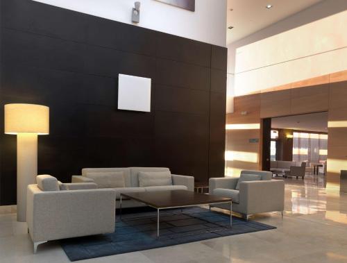a lobby with chairs and a table and a wall at NH Campo de Gibraltar in Los Barrios