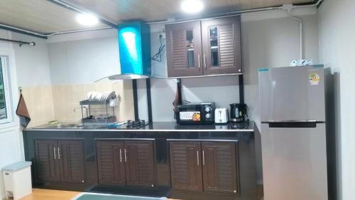 a kitchen with brown cabinets and a refrigerator at Tanakorn House in Thong Nai Pan Yai