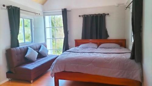 a bedroom with a bed and a couch and windows at Tanakorn House in Thong Nai Pan Yai