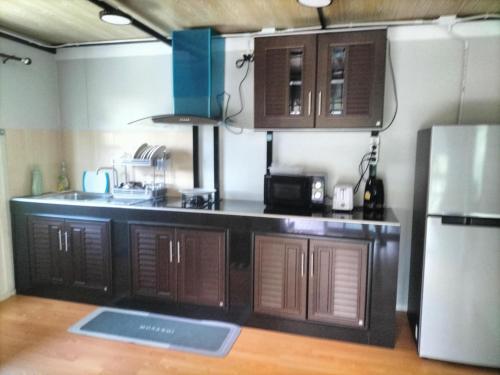 a kitchen with wooden cabinets and a refrigerator at Tanakorn House in Thong Nai Pan Yai
