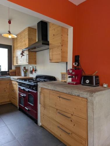 une cuisine avec une cuisinière rouge et des armoires en bois dans l'établissement House surrounded by nature, à Callian
