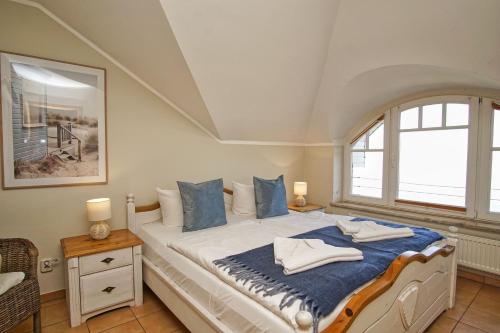a bedroom with a bed with blue pillows and a window at Ferienwohnung mit traumhaftem Meerblick - Haus am Meer FeWo 10 in Lohme