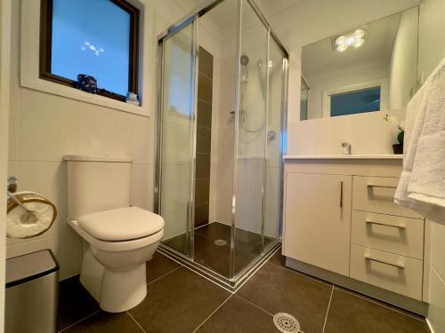 a bathroom with a toilet and a glass shower at The Nest at Crace in Ginninderra