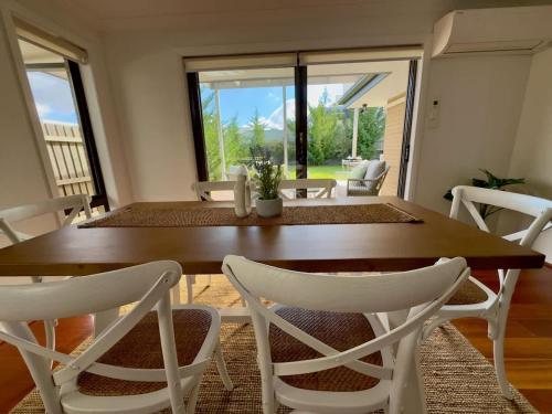 a dining room with a wooden table and white chairs at The Nest at Crace in Ginninderra