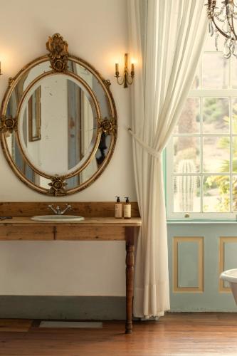 a bathroom with a mirror and a sink and a window at Hotel Emblemático La Casa de los Naranjos in Haría