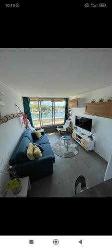 un salon avec un canapé bleu et une grande fenêtre dans l'établissement Studio cabine à Port Camargue, au Grau-du-Roi