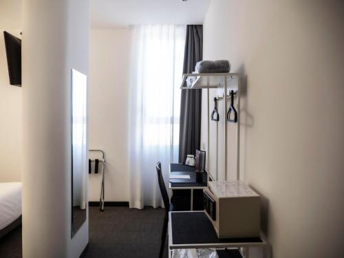 a hotel room with a desk with a television and a bed at Loto Business Hotel in Rome
