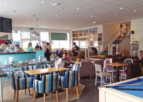 a restaurant with tables and chairs and people in it at Atlantic Reach Holiday Village in Newquay