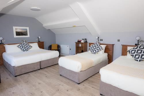 two beds in a room with white and brown pillows at Aran Islands Hotel in Kilronan