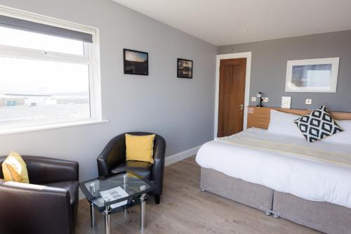 a bedroom with a bed and a chair and a table at Aran Islands Hotel in Kilronan