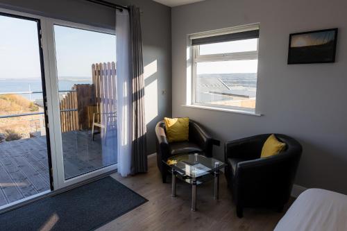a room with two chairs and a table and a balcony at Aran Islands Hotel in Kilronan