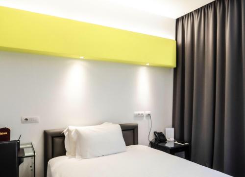 a hotel room with a bed and a yellow wall at Loto Business Hotel in Rome