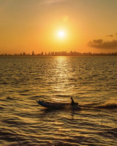 a person in a boat in the water at sunset at Pousada Recanto do Sabiá in Barcarena
