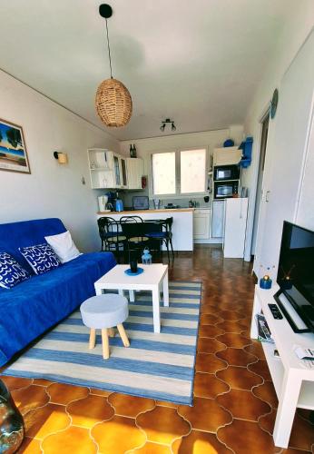 un salon avec un canapé bleu et une table dans l'établissement T2 belle terrasse avec vue sur mer, à Port-Vendres