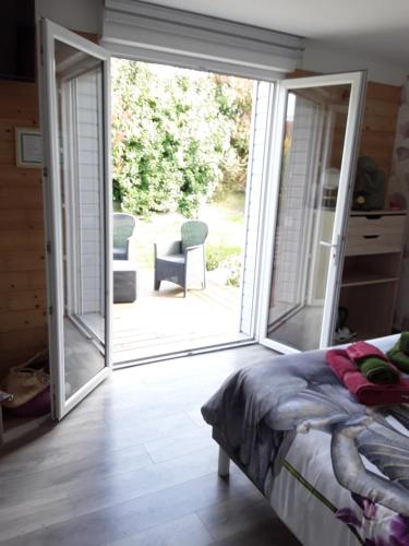a bedroom with a door open to a patio at Chambres d'hôtes de L'orval in Thiergeville