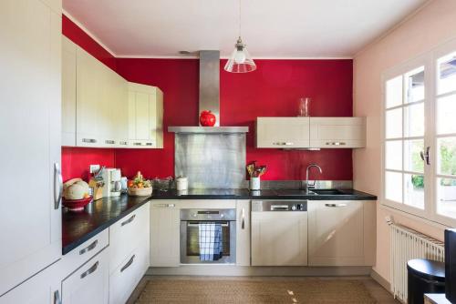 - une cuisine avec des murs rouges et des armoires blanches dans l'établissement Villa Cap Ferret, à Lège-Cap-Ferret