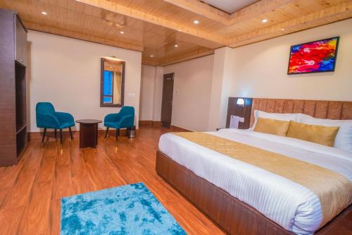 a bedroom with a large bed and two blue chairs at Divine The Celeste, Pelling in Pelling