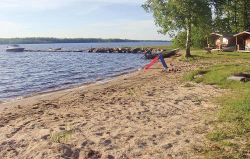 a sandy beach next to the water with a boat at Lovely Home In Bolmsö With Sauna in Bolmsö