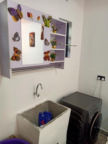 a bathroom with a sink and a toilet with butterflies on the wall at Camp William's - A dreamer's paradise in Kiambu in Kanyore