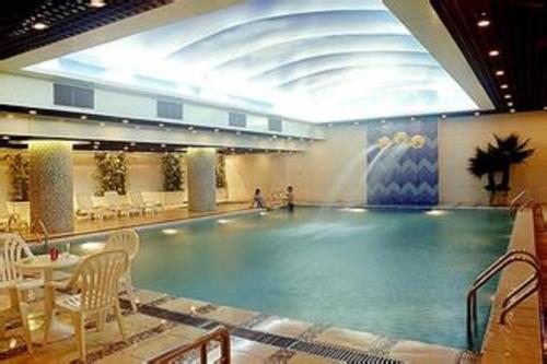 a large swimming pool with a fountain in a building at Grand Metropark Wanshi Hotel Taiyuan in Taiyuan