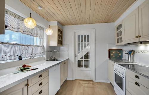 a kitchen with white cabinets and a large window at Holiday Home Nykobing I in Ejerslev