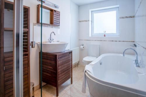 a white bathroom with a tub and a sink at Nottage Road - 3 Bedroom Holiday Home - Mumbles in Swansea