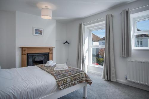 a white bedroom with a bed and a fireplace at Nottage Road - 3 Bedroom Holiday Home - Mumbles in Swansea