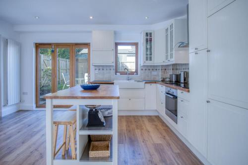 a kitchen with white cabinets and a wooden island at Nottage Road - 3 Bedroom Holiday Home - Mumbles in Swansea
