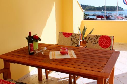 a wooden table with a bottle of wine and two chairs at apartments RIVA in Pakoštane