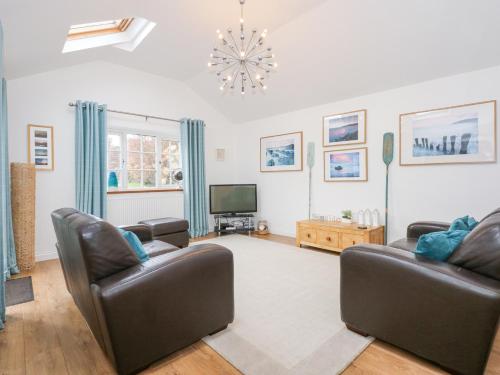 a living room with two leather chairs and a television at Pippin Cottage in Beaumaris
