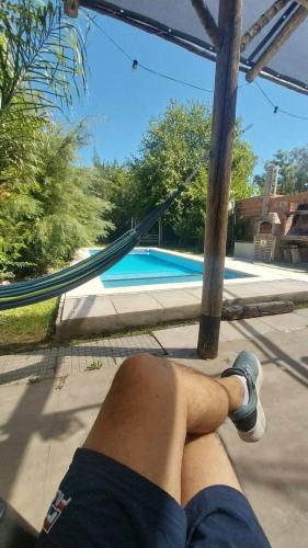 a man laying on a hammock next to a swimming pool at CasaClubDescanso in General Rodríguez