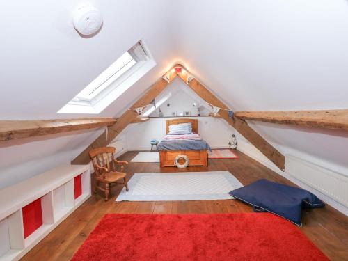 a attic bedroom with a bed and a red rug at Bramley Cottage in Beaumaris