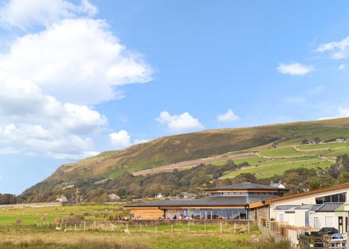 a building in a field with a hill in the background at Sunbeach Holiday Park in Llwyngwril