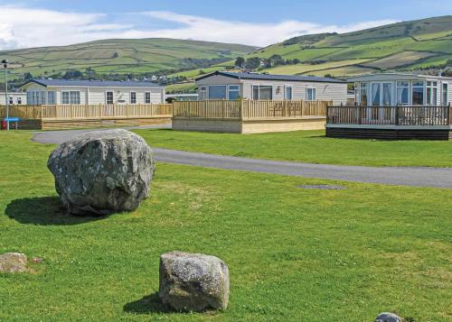 a rock in the middle of a field with houses at Sunbeach Holiday Park in Llwyngwril