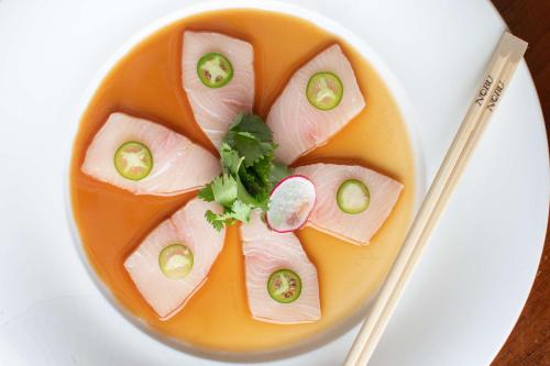 a plate of food with a fish with cucumbers and chopsticks at Nobu Hotel Toronto in Toronto