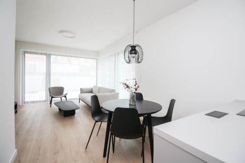 a white living room with a table and a couch at Rodinný apartmán se zahradou TRE Mikulov in Mikulov