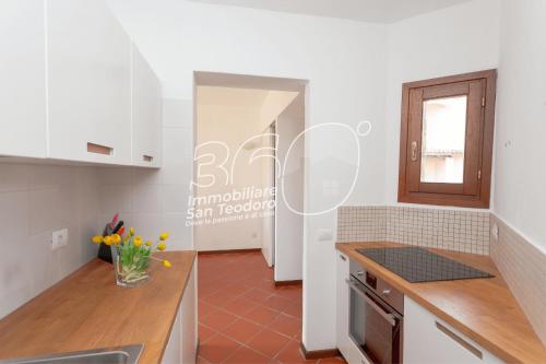 a kitchen with white cabinets and a red tile floor at Trilo Galathee 6 in Puntaldia