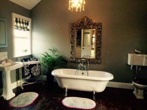 a bathroom with a tub and a mirror on the wall at Cavan House in Rathfriland