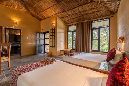 a bedroom with two beds in a room with windows at Jungle Villa Resort - Near Chitwan National Park in Chitwan