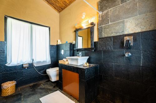 a bathroom with a sink and a toilet and a window at Jungle Villa Resort - Near Chitwan National Park in Chitwan