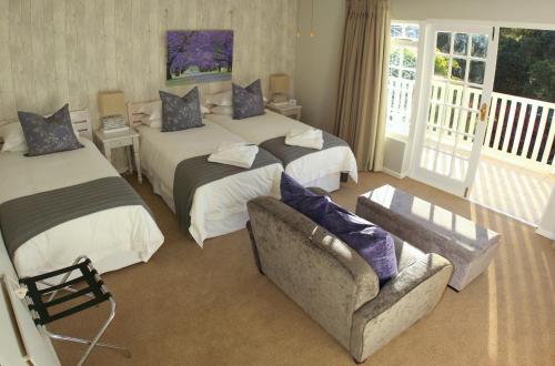 a hotel room with two beds and a couch at Lodge on Main Guest House and Conference Centre in Port Elizabeth