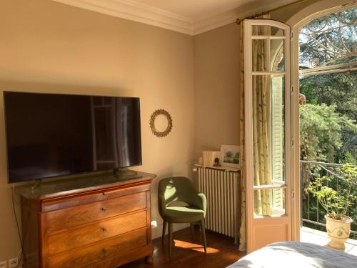 a bedroom with a television on a dresser and a chair at House facing Roland Garros stadium - 5 bedrooms in Boulogne-Billancourt