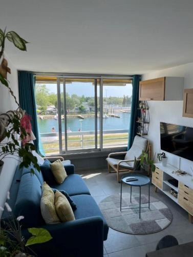 un salon avec un canapé bleu et une grande fenêtre dans l'établissement Studio cabine à Port Camargue, au Grau-du-Roi