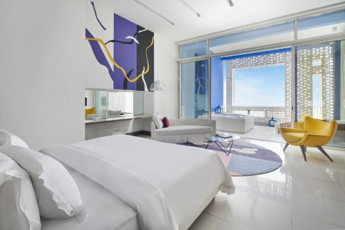 a white bedroom with a bed and a living room at Sofitel Tamuda Bay Beach And Spa in M'diq