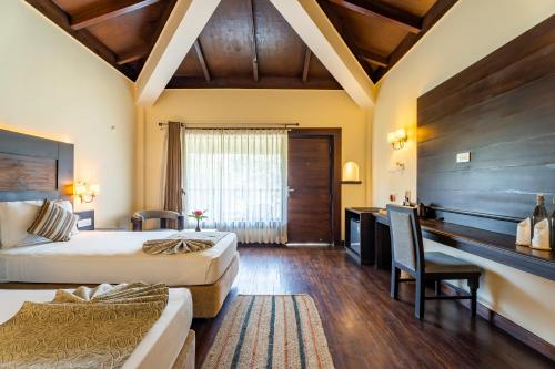 a hotel room with two beds and a desk at Jungle Villa Resort - Near Chitwan National Park in Chitwan