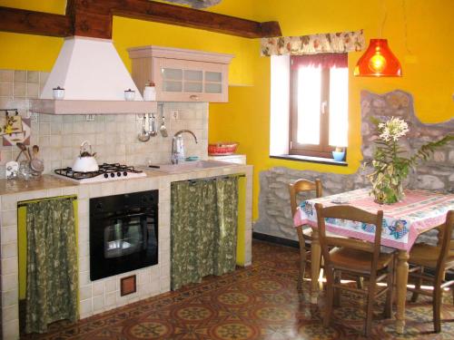 a kitchen with a table and a kitchen with yellow walls at Apartment Limone by Interhome in Dolcedo