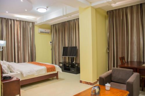 una stanza d'albergo con un letto, una sedia e una televisione di Hong Kong Hotel a Dar es Salaam