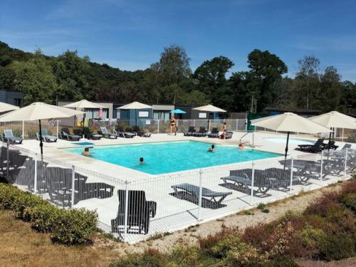 a large swimming pool with chairs and umbrellas at Holiday Home Le Moulin Neuf- 2-4 personnes by Interhome in Rochefort-en-Terre