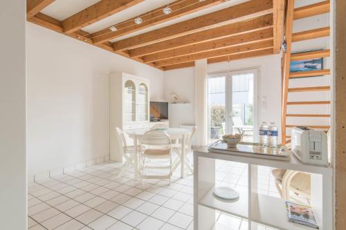 Il comprend une cuisine et une salle à manger avec des murs blancs et des plafonds en bois. dans l'établissement LES SAULES - 750m plage - Parking, à Pornichet