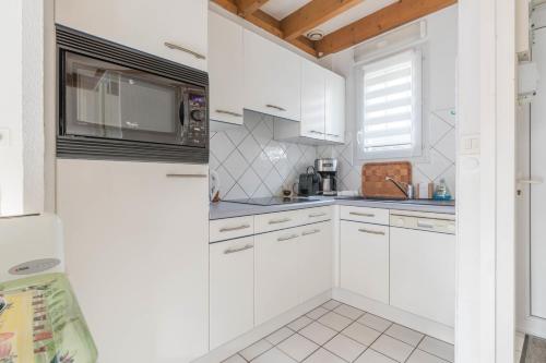 une cuisine blanche avec des armoires blanches et une fenêtre dans l'établissement LES SAULES - 750m plage - Parking, à Pornichet